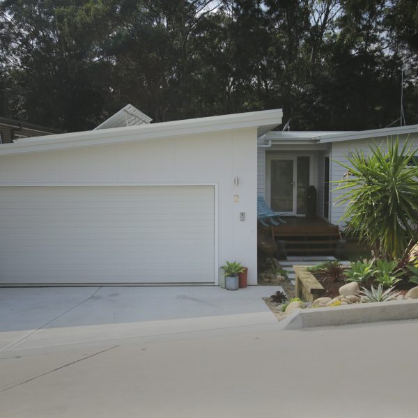 Modern family-friendly home exterior with garage, landscaped garden, and sustainable design features, showcasing Living Green Designer Homes' commitment to energy efficiency.