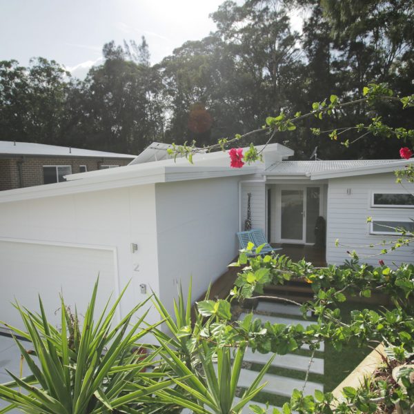 Modern family-friendly home design with sustainable features, landscaped garden, and inviting entrance, showcasing Living Green Designer Homes' commitment to energy efficiency.