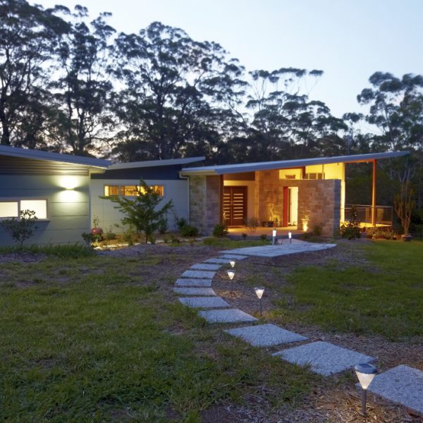 Sustainable eco-home exterior with stone pathway, landscaped garden, and modern architecture, showcasing Living Green Designer Homes' Hilltop Hideaway project.