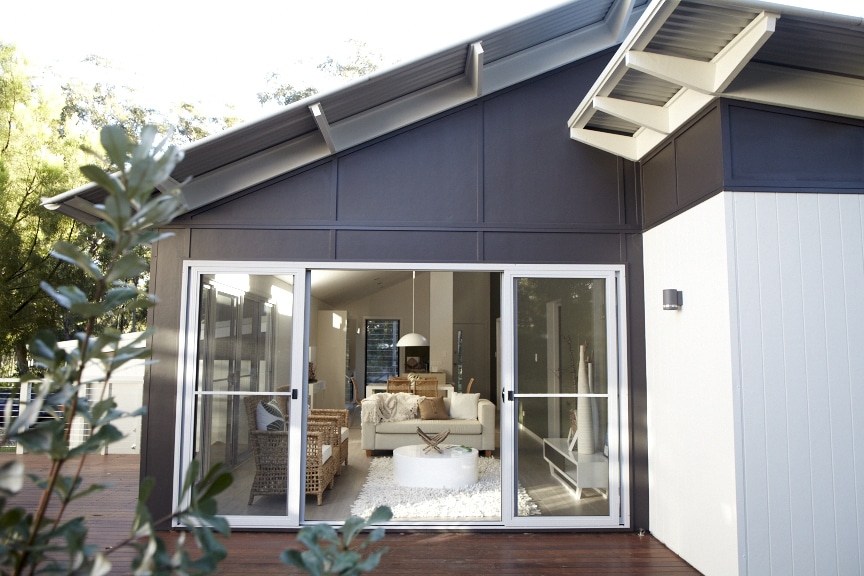 Modern eco-friendly home exterior showcasing energy-efficient design, featuring large glass doors leading to a stylish interior with natural decor elements and sustainable materials.