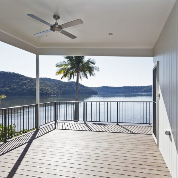 Sustainable deck with scenic river view, featuring a ceiling fan, palm tree, and modern railing design.