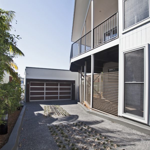 Sustainable home design featuring a modern exterior with a balcony, garage, and landscaped driveway, showcasing Living Green Designer Homes' innovative construction techniques.