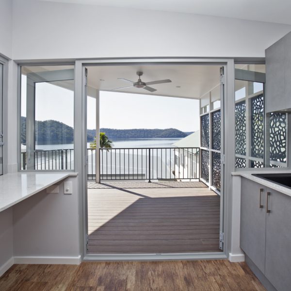 Sleek interior view of a sustainable home showcasing a spacious balcony with a scenic river view, emphasizing modern design and natural light.