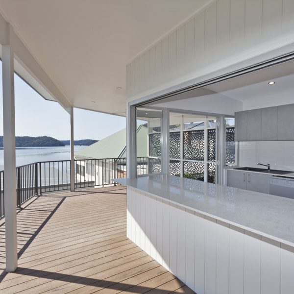 Modern outdoor kitchen with a marble countertop, overlooking a serene river view, featuring large windows and sustainable design elements.