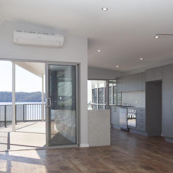 Modern kitchen and living area with sliding glass door, showcasing sustainable design and river view, part of Living Green Designer Homes' River View Homes project.