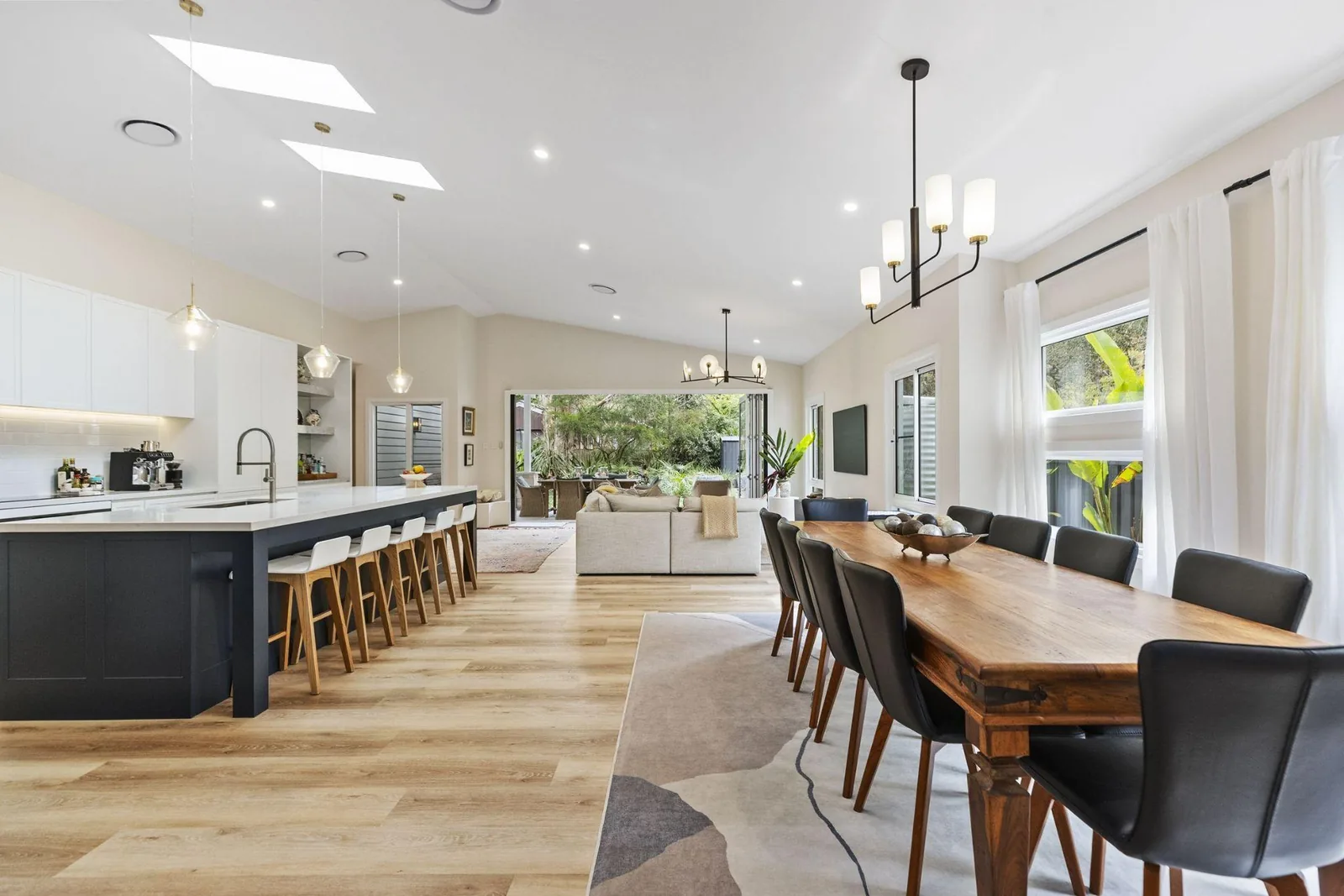 Open-plan kitchen, dining and living area with a vaulted ceiling in a custom Central Coast home